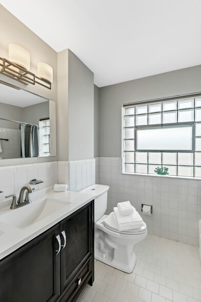 Updated bathroom. Linen closet is in foyer to the right of bath. Tub shower combo. Glass block window allows for privacy with ventilation window. Little nook is perfect for small shelving unit. - 3443 Lawn Ave