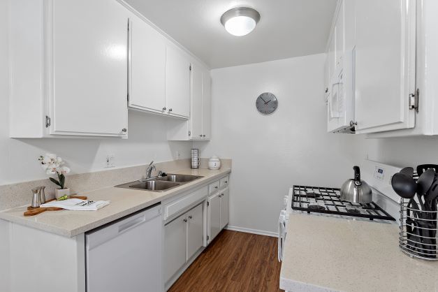 Upgraded kitchen with plank flooring and kitchen appliances which includes a gas range, dishwasher, and a built-in microwave at the Ridgeview Apartment in Northridge - The Ridgeview