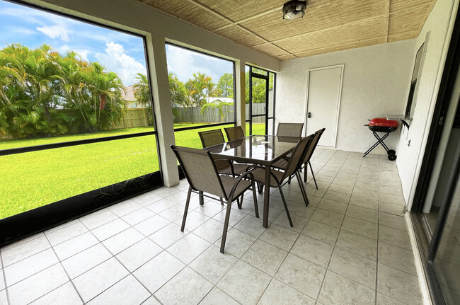 Spacious screened patio with outdoors dining table, chairs and charcoal grill - 722 SE Thanksgiving Ave