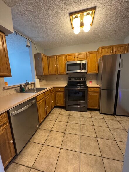 Kitchen features modern fridge/freezer, new dishwasher, glass cooktop, all stainless steel - 705 Lake Ave