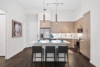 Kitchen with oak cabinetry, undercabinet lighting, white quartz countertops, and hard-surface vinyl plank flooring - Avalon Fort Lauderdale