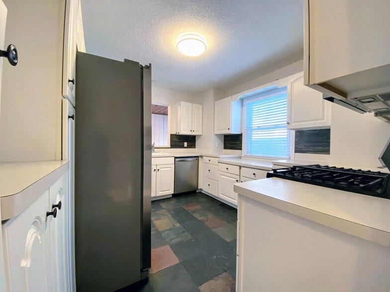 Kitchen - White cabinetry, updated stainless steel appliances, and slate tile floors - 710 Sheridan Avenue North