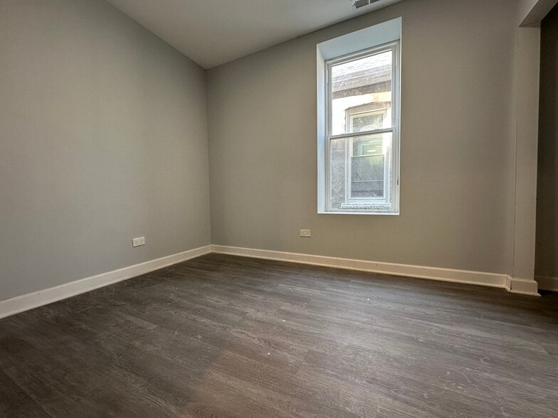 Bright bedroom with a large window and brand-new flooring - 5653 S May St