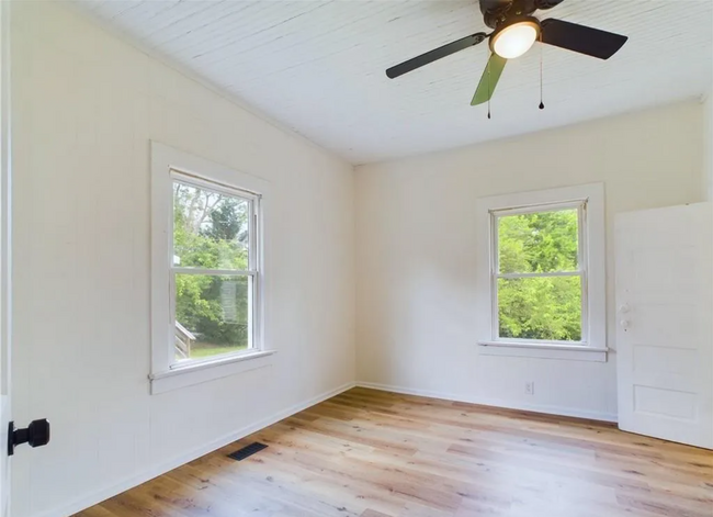 Living Room: Bright and inviting featuring beautiful wood floors and a ceiling fan for added comfort - 1011 Elm St