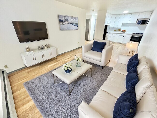 Experience the blend of comfort and style in this chic living area and open kitchen. - Melody Apartments