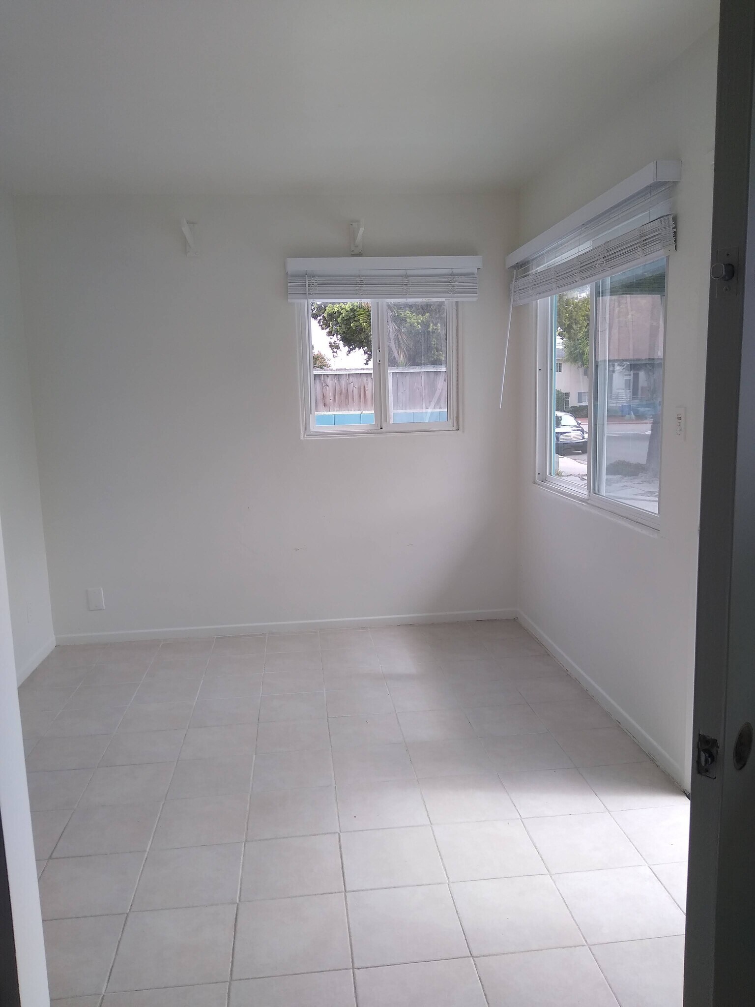 Living Room with surf rack, built-in wall heater and large windows. Tile flooring throughout. - 4127 Everts St