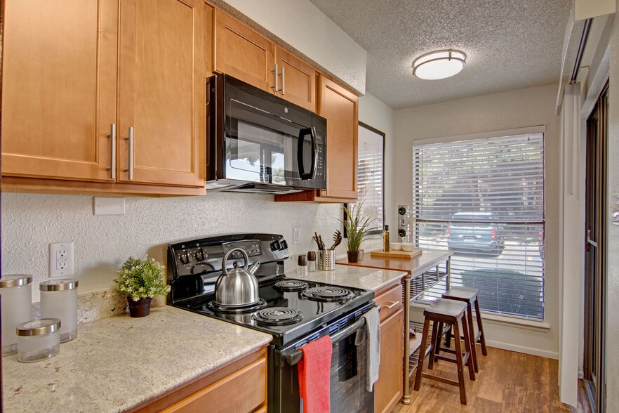 A kitchen with light cabinets and black appliances - Motif