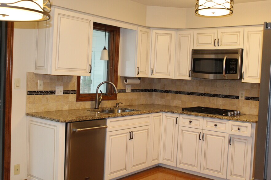 Updated kitchen with white cabinetry, granite countertops, and stainless steel appliances. - 6235 Sunnywood Dr
