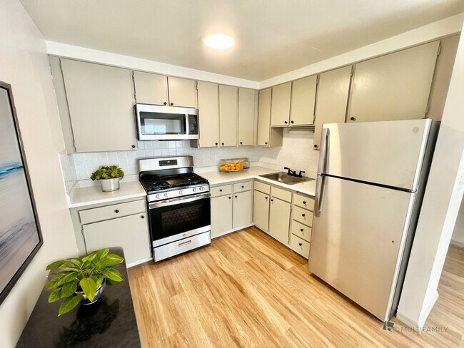 Step into a stylish kitchen featuring top-tier appliances and elegant design. - Harmony Apartments