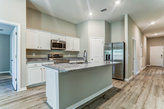 a kitchen with white cabinets and a marble counter top - Cottages at Parkstone