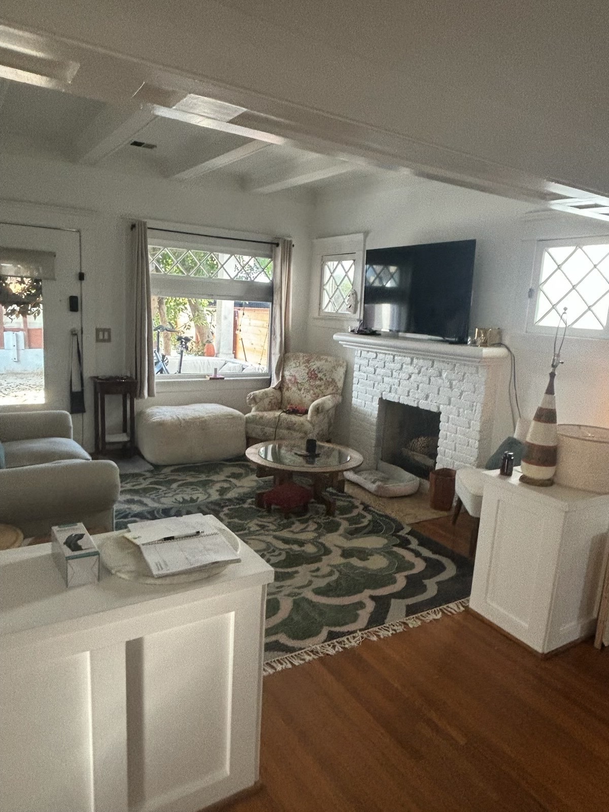 Inviting living room with original hardwood floors, decorative fireplace, and beamed ceiling. - 6000 Carlton Way