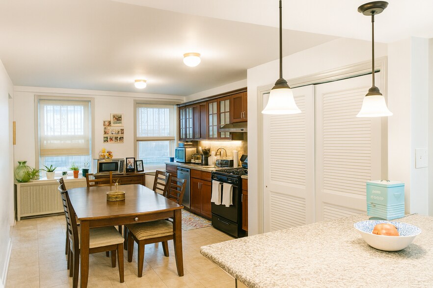 Modern kitchen featuring a vented exhaust hood, built-in dishwasher, and generous cabinet space - 56 Jefferson Ave