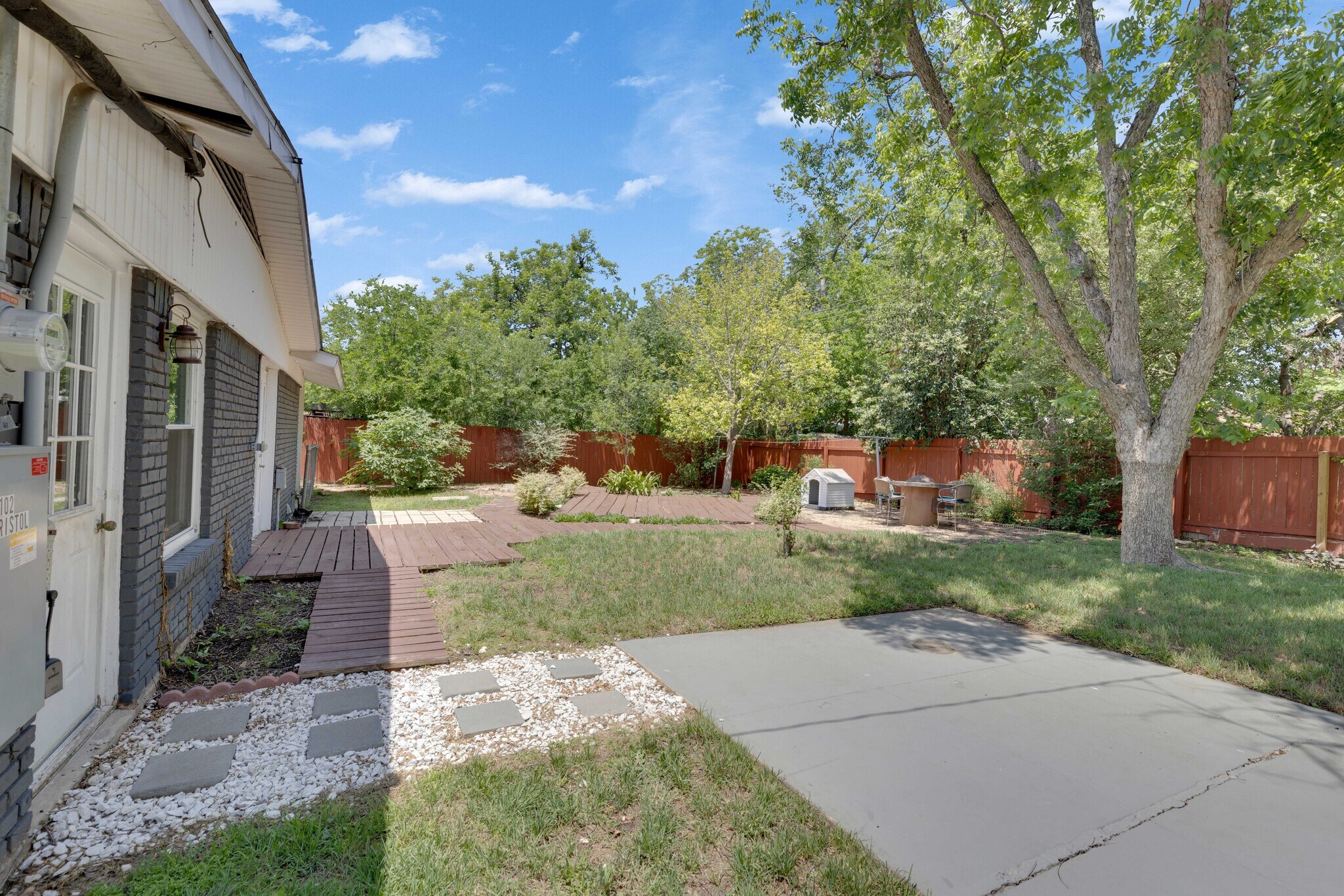 Backyard seating areas are connected by stone and wooden pathways - 2102 Bristol Dr