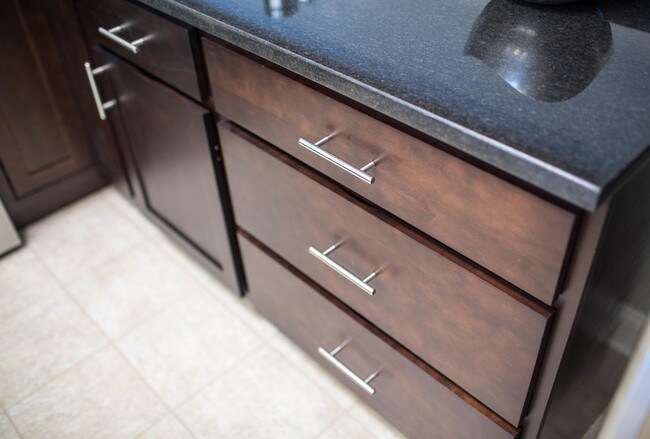 Modern Hardware, Espresso Kitchen Cabinets, Granite Countertops - Stonegate at the Crossroads Apartments