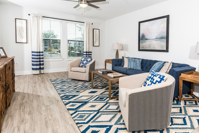 Beautifully decorated model living room with wood inspired flooring and ceiling fan with light fixture - The Haven at Indigo Square