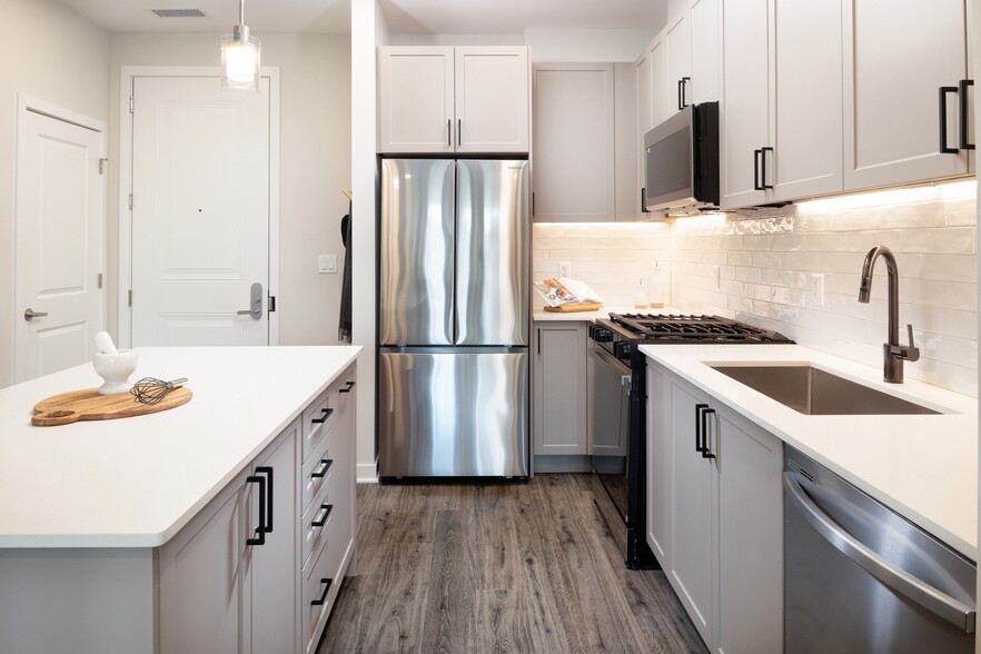 Modern with grey cabinetry, white quartz countertops, white tile backsplash, and stainless-steel appliances - Avalon Princeton on Harrison