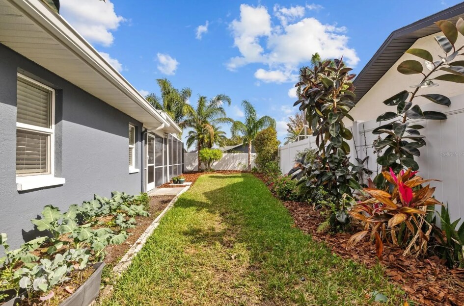 Beautifully landscaped side yard with lush tropical greenery. - 1932 Brainerd Ct