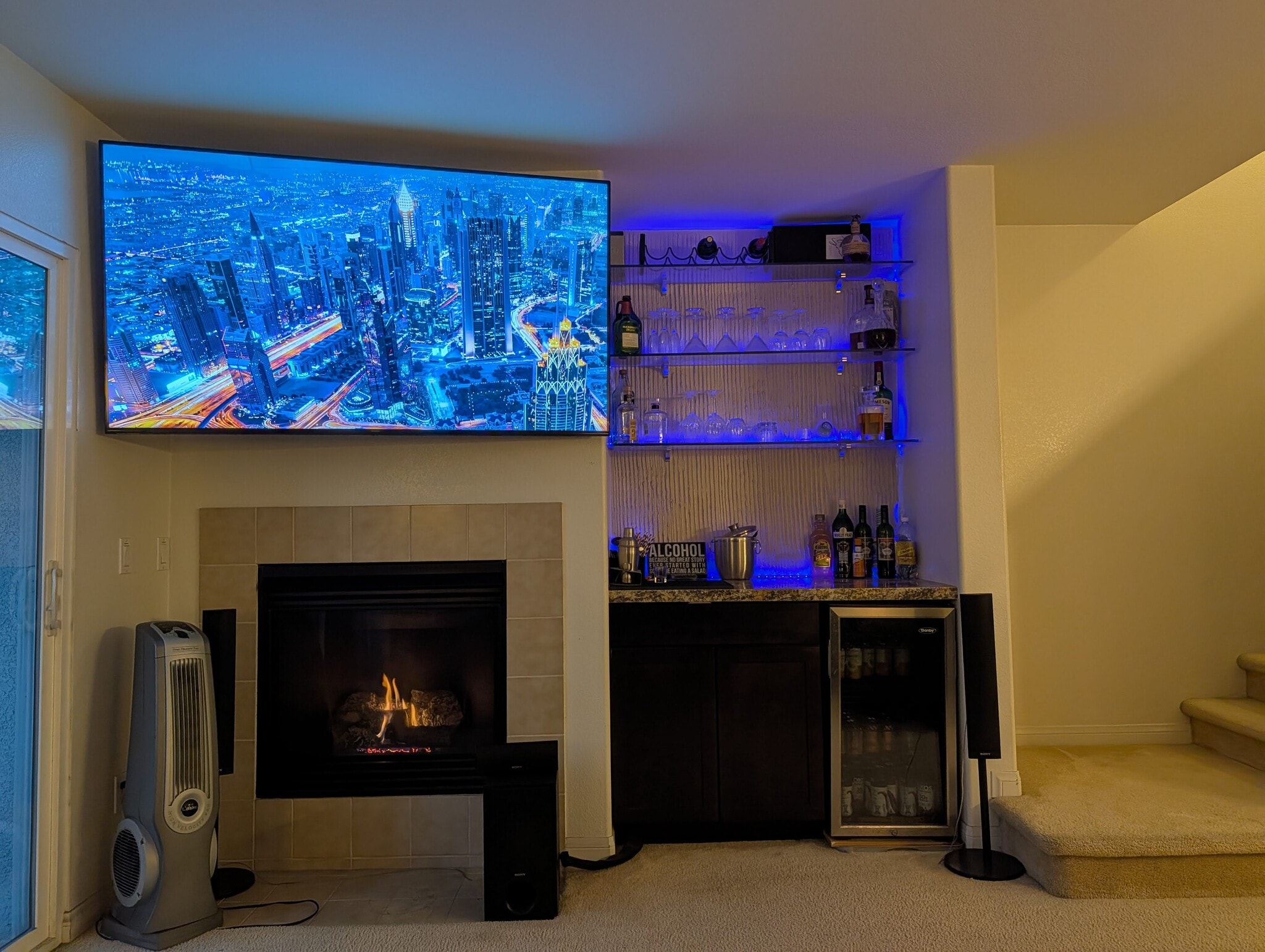 Living room TV, fireplace, bar, mini-fridge, and hidden entertainment center. - 3542 Shoreline Bluff Lane
