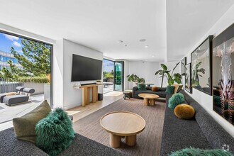 Bright and modern living room with stylish furniture, lush green plants, and a seamless flow to a sunlit outdoor patio. - The Rise Walnut Creek
