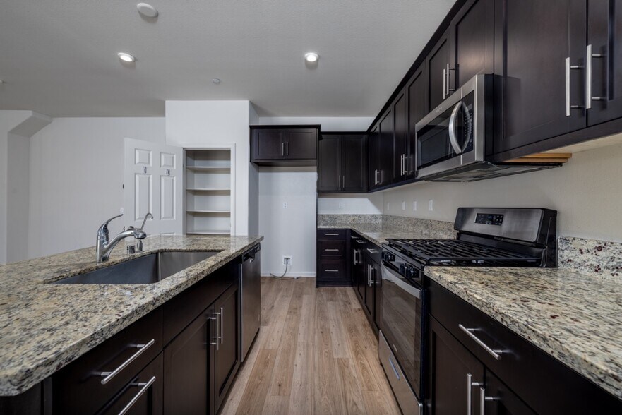 Modern kitchen with granite countertops, dishwasher, and ample cabinet storage. - 26549 Brightstone Dr