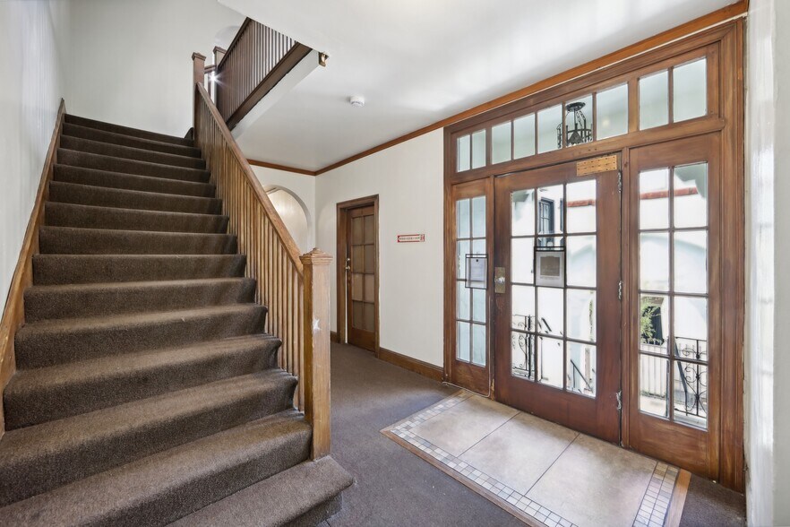Hallway with a wooden staircase and banister, a wooden door with glass window - 2410 Dwight Way