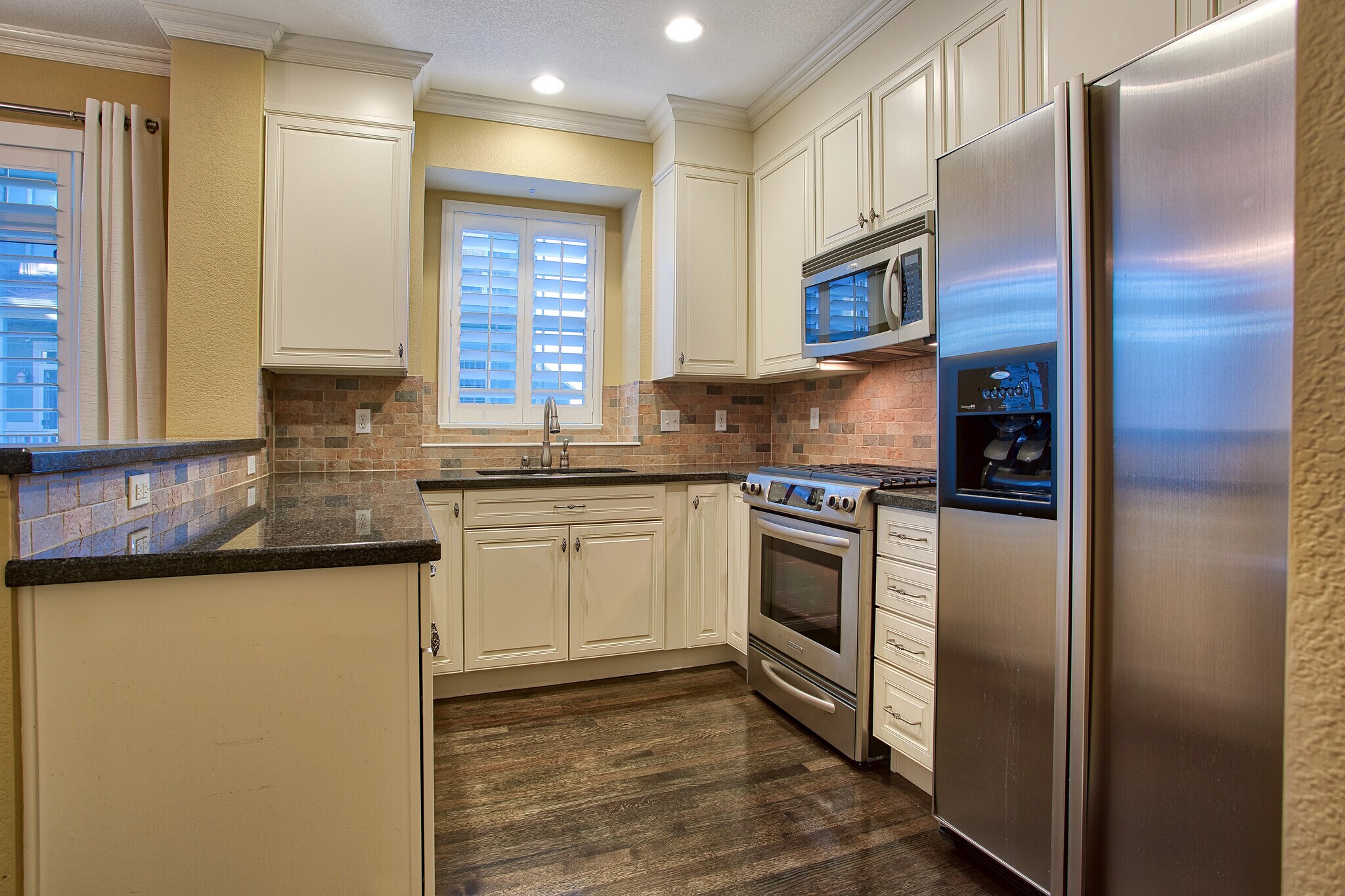 Kitchen with slab granite counters, gas stove, microwave, dishwasher, stainless appliances - 7422 E 7th Ave Unit 14
