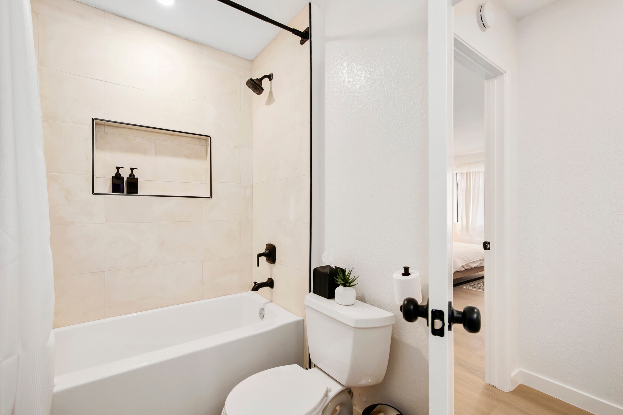 Modern bathroom with deep soaking tub and matte black fixtures. - 1013 S Sunshine Ave