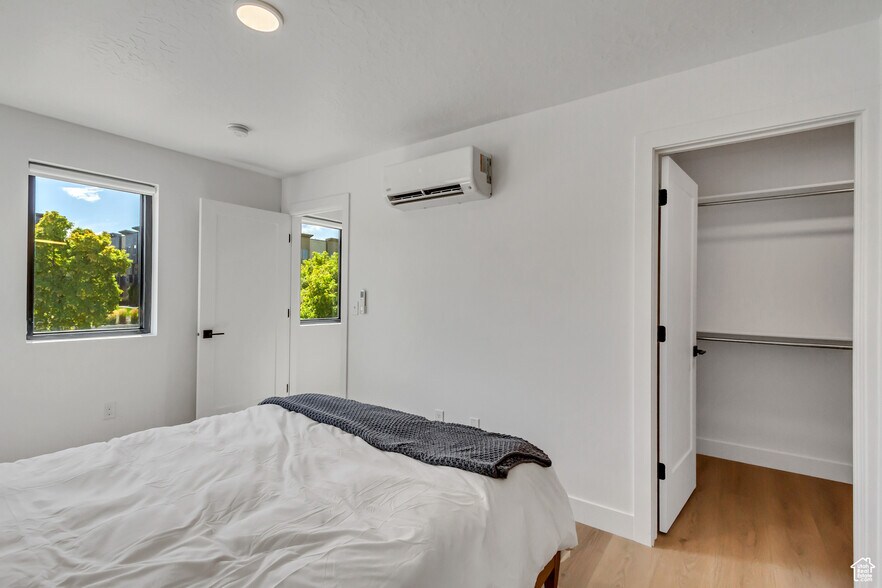 bedroom with connected bathroom,multiple windows, and light wood-style flooring - 44 W Iko Ave