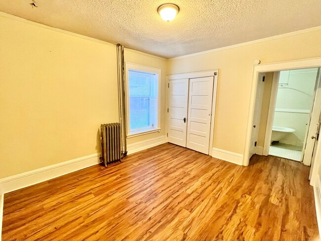 Step into your new cozy bedroom, featuring elegant hardwood floors and ample storage. - Cross Apartments