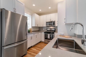 Renovated Package II kitchen with white cabinetry, grey quartz countertops,  grey subway tile backsplash, stainless steel appliances, and hard surface flooring - Avalon Northborough