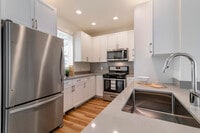 Renovated Package II kitchen with white cabinetry, grey quartz countertops,  grey subway tile backsplash, stainless steel appliances, and hard surface flooring - Avalon Northborough