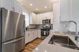 Renovated Package II kitchen with white cabinetry, grey quartz countertops,  grey subway tile backsplash, stainless steel appliances, and hard surface flooring - Avalon Northborough