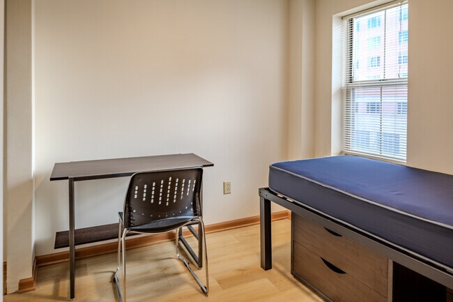 Fully furnished bedroom with bed, desk and storage - Varsity Campus Apartments