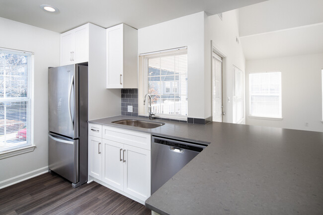 Kitchen with gray quartz countertops, tile backsplash, stainless steel appliances, and upgraded fixtures - Avalon at Bedford Center