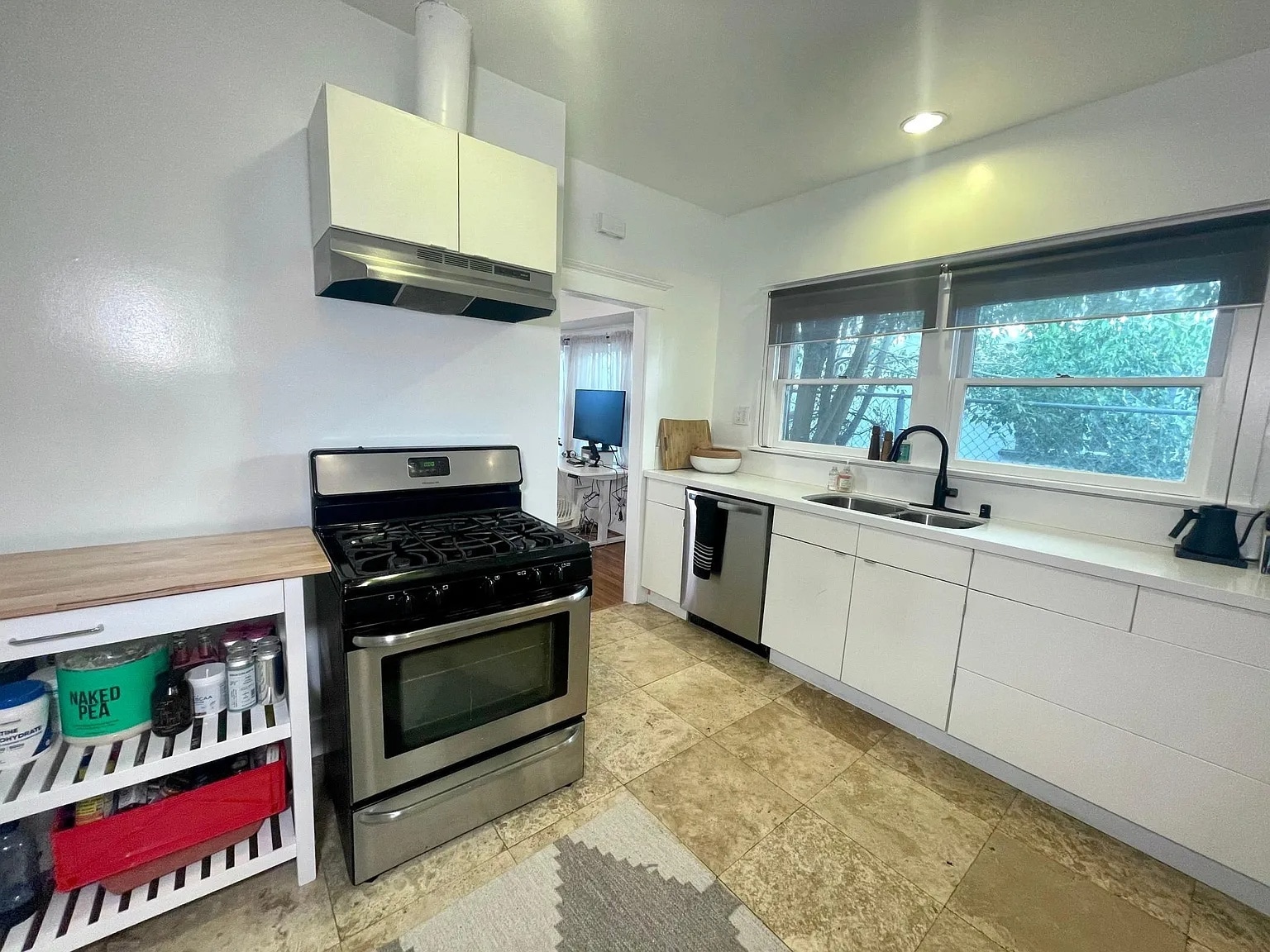 Open kitchen layout with double sink, gas stove, and modern counters. - 6000 Carlton Way