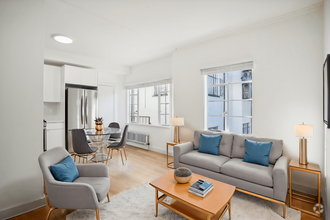 Living room with large window allowing natural light to flood the space, features a sofa. coffee table, dining table with chairs and a refrigerator - 2363 Le Conte Avenue