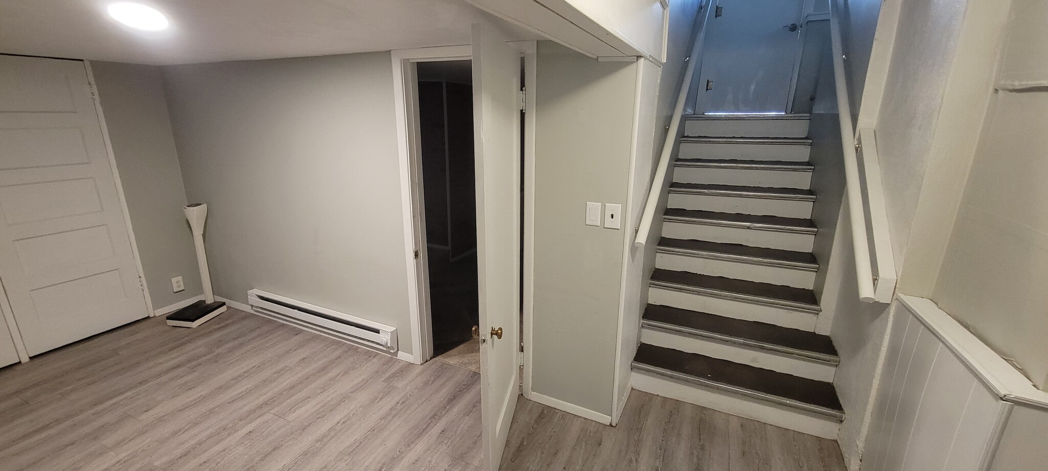 Bottom of stairs in the lower level is an open area, with the bathroom door seen (open), water heate - 814 Atchison Ave