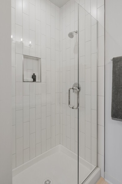 Frameless glass shower with vertical tile detail and built-in niche. - 358 E Village Ln
