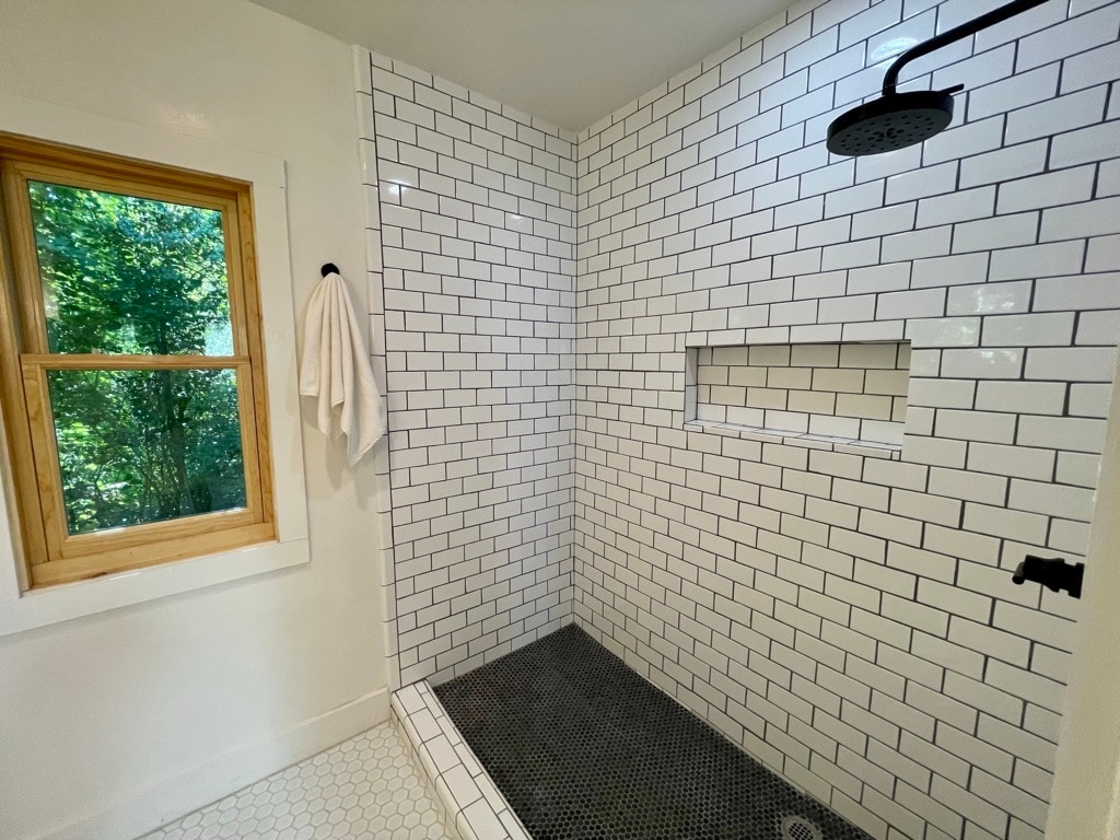 Primary suite bathroom, large subway tiled shower with shampoo shelf, exhaust fan and two windows. - 6605 Shady Lake Ln