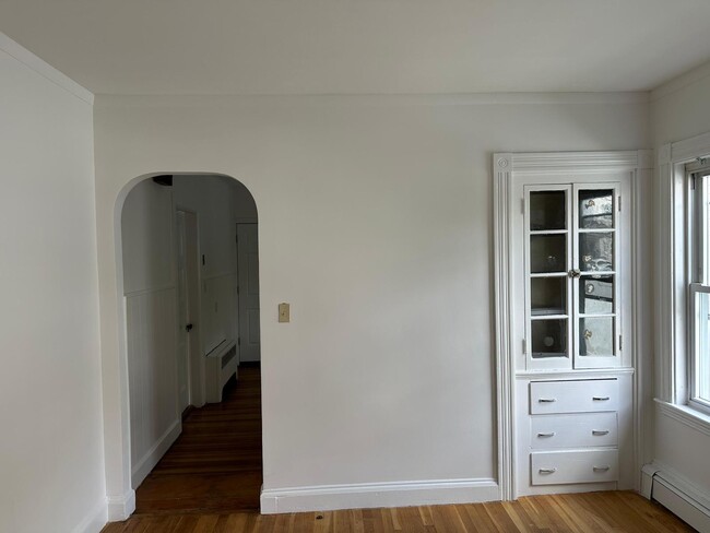 Living area w/ charming built-in cabinet, closet for storage, and natural light. - 58 S Waverly St