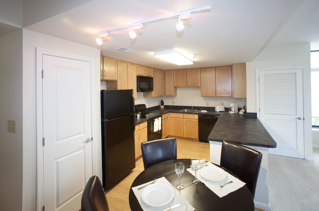 Dining area and kitchen with black appliances, black countertops and hard surface flooring - Kanso Silver Spring