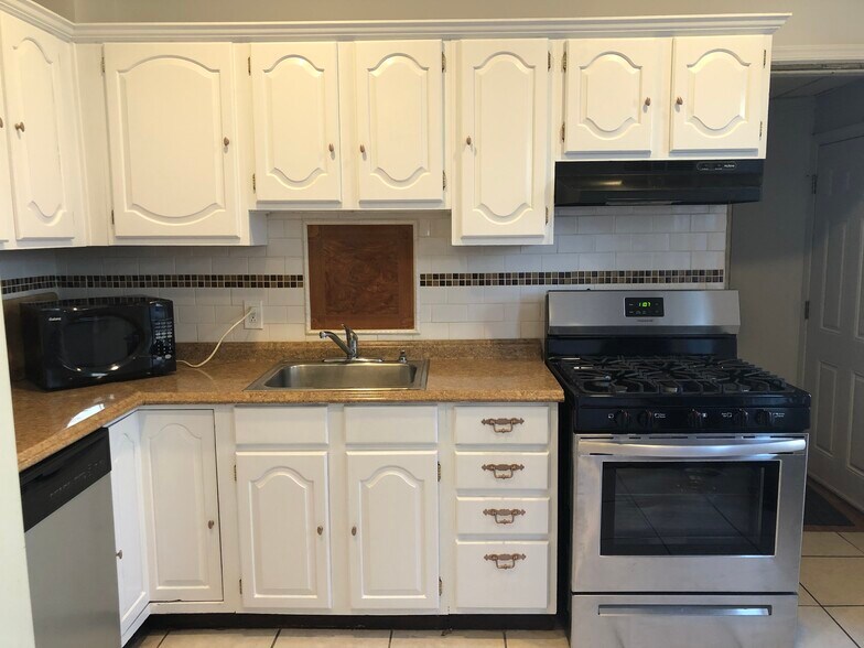 "L" shaped Large Eat-In Kitchen with new Stainless Steel Gas Stove, white Hardwood Cabinets. White Subway Tiled Backsplash. Tiled floor - 263 West Rittenhouse Street