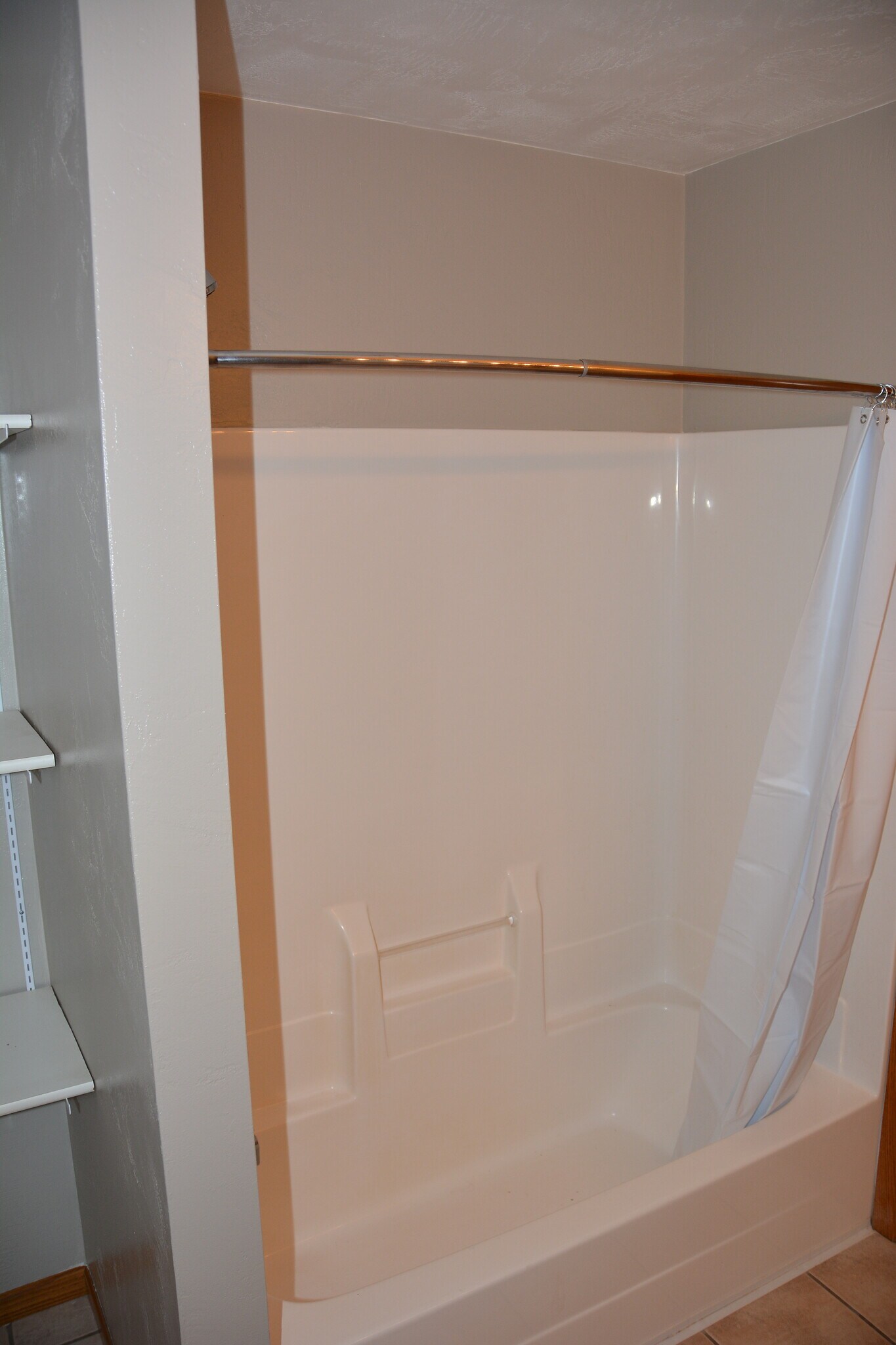 Main Bathroom with storage shelves and one piece tub/shower surround. - 325 Cordy Lane