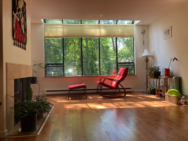 Living room with large windows looking out onto the lake and greenery. - 6 Lake Bellevue Dr