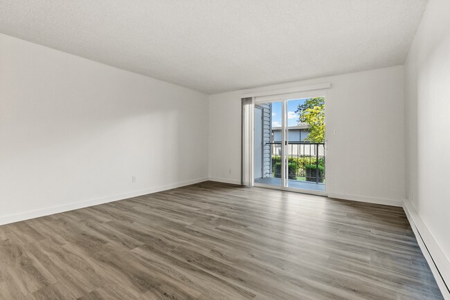 Relax in a bright, open living room featuring modern flooring and direct access to your private balcony for fresh air and natural light. - Bay Ridge Apartments
