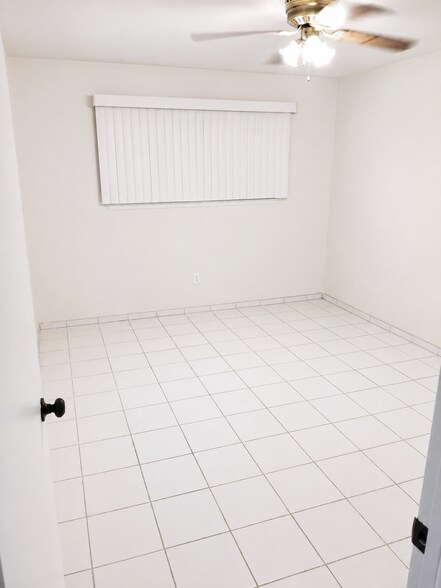 Comfortable second bedroom with neutral walls, tile flooring, ceiling fan, and closet space. - 339 E Taft Ave