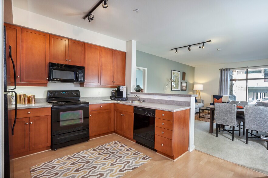 Classic Package I kitchen with black or white appliances, cherry cabinetry, laminate countertops, and hard surface flooring - Avalon at Cahill Park