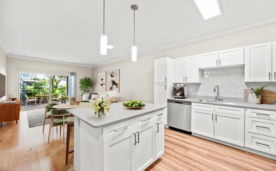 Open-concept kitchen with shaker-style cabinetry, a spacious prep island, and seamless flow into the dining and living areas for easy everyday living. - The Avens at Dedham Station