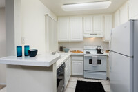 Classic kitchen with white tile countertops, white cabinetry, white appliances, and tile flooring - eaves Warner Center