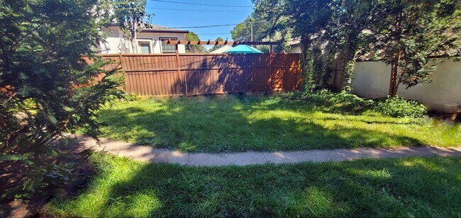Spacious, fenced backyard with grass and mature trees. - 2923 Arthur St NE
